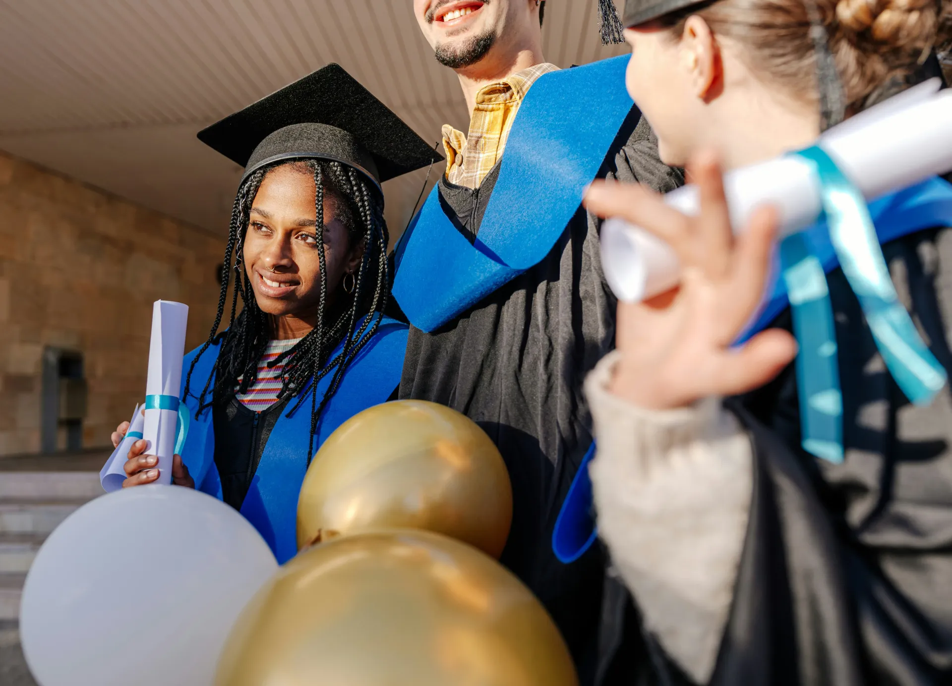 Happy university graduates celebrating with diplomas and balloons.