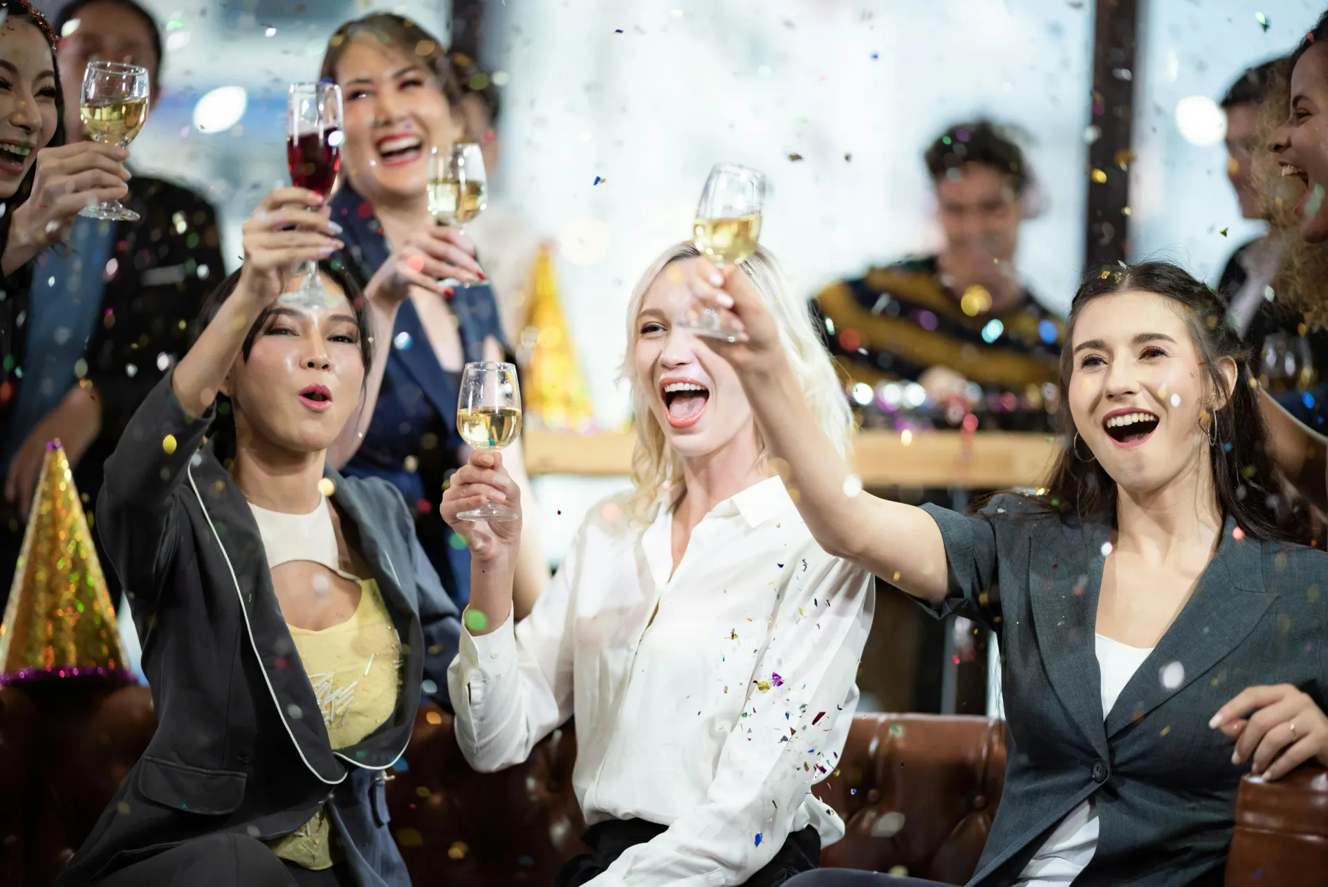 Joyful guests raising glasses with confetti falling at a lively corporate event or celebration, displaying the fun party atmosphere.