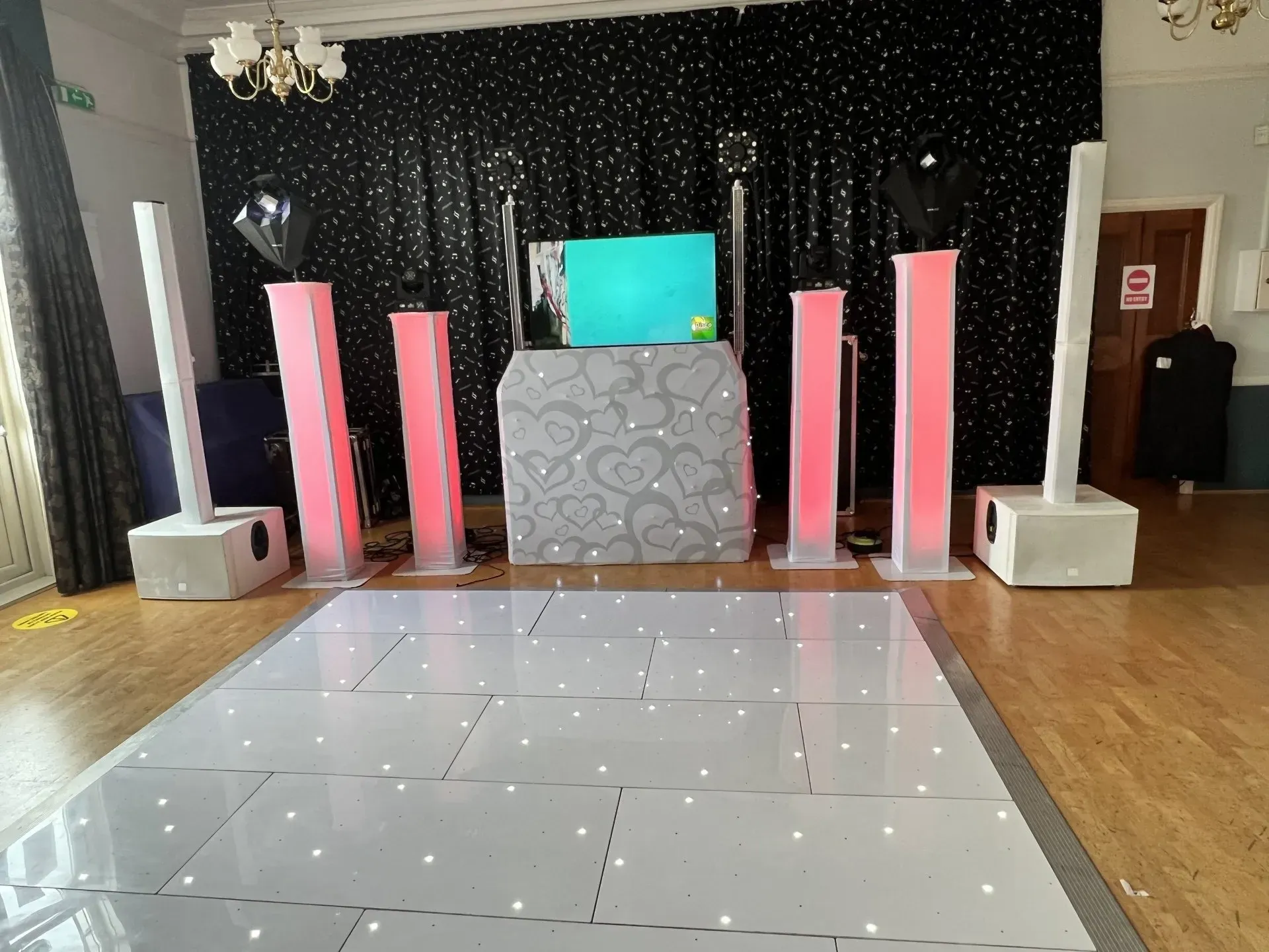 Professional wedding or party DJ setup featuring a white LED starlit dancefloor, illuminated DJ booth, speakers, and pink LED uplighting.