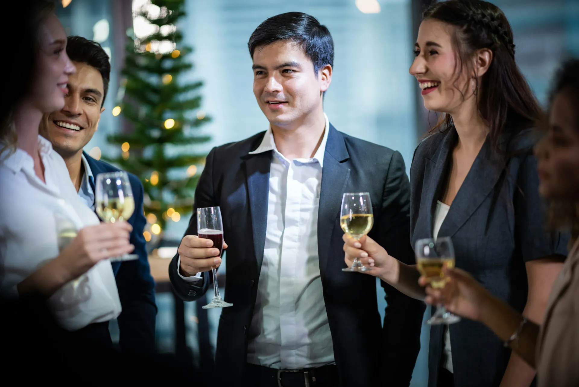 Smiling colleagues enjoying drinks and conversation at a corporate Christmas party or staff appreciation event.