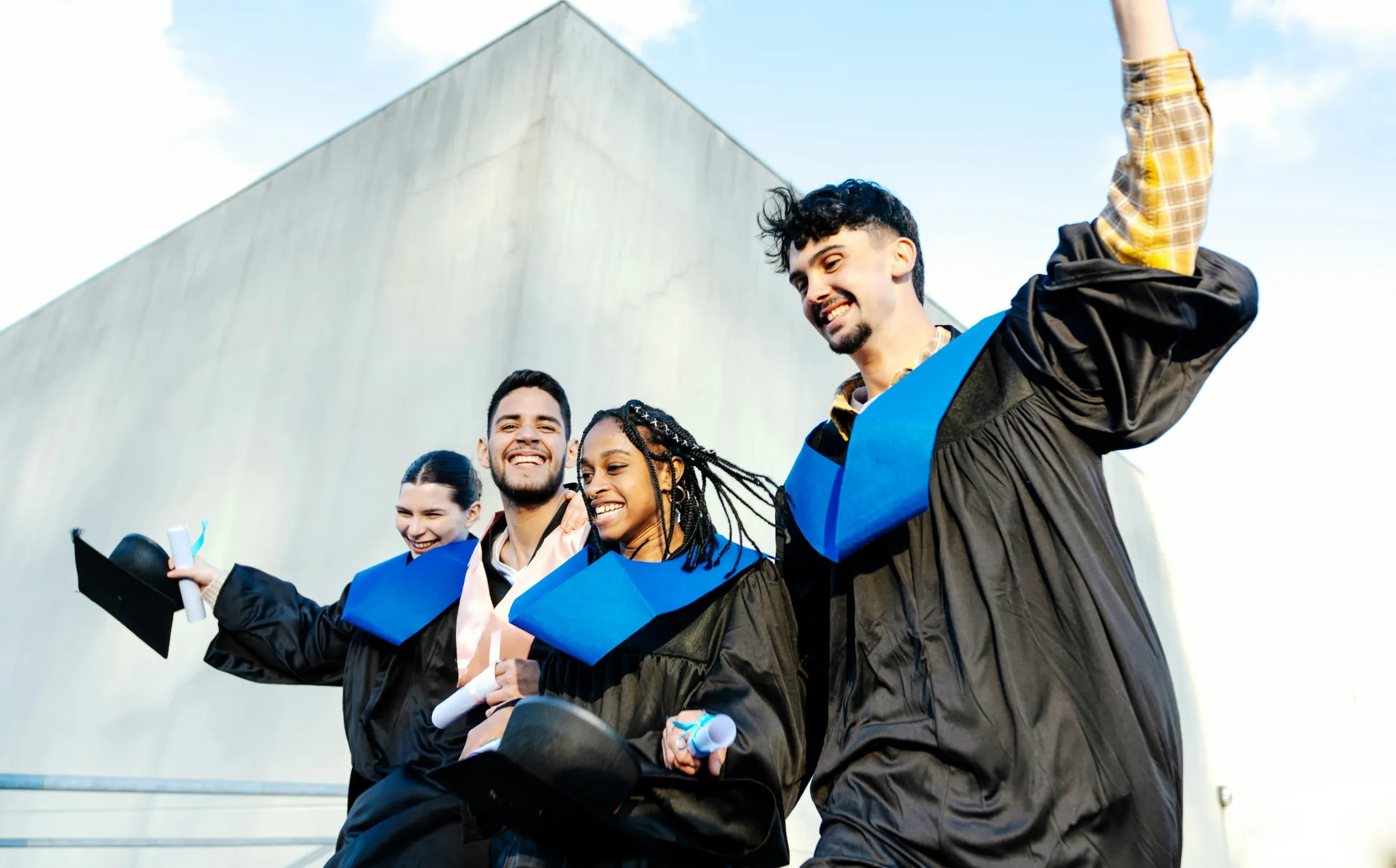 Joyful group of diverse university graduates in caps and gowns celebrating their special day with diplomas in hand.